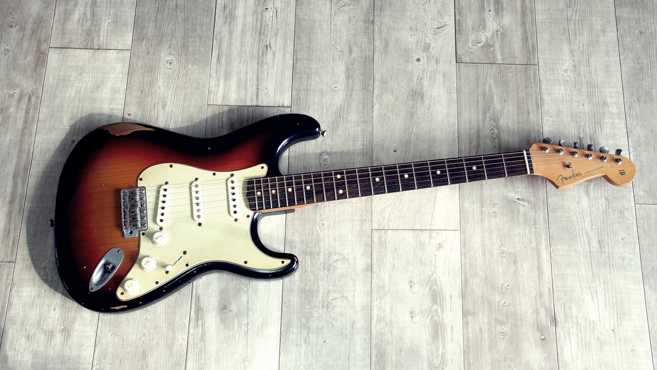 Электрогитара лежит на деревянном полу