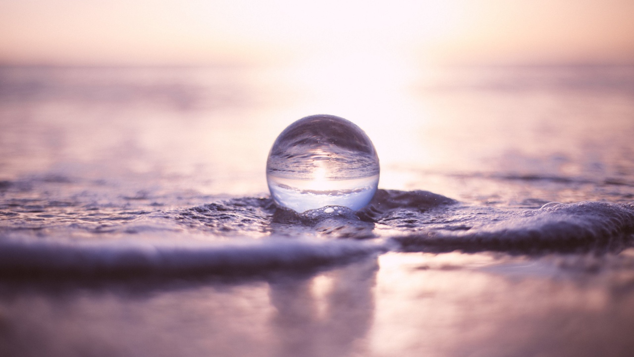 Прозрачный стеклянный шар лежит на пене в море