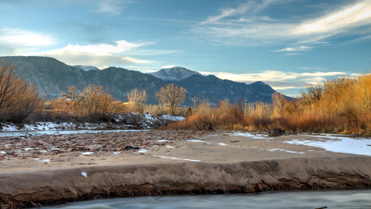 Каменный берег реки на фоне гор под голубым небом 