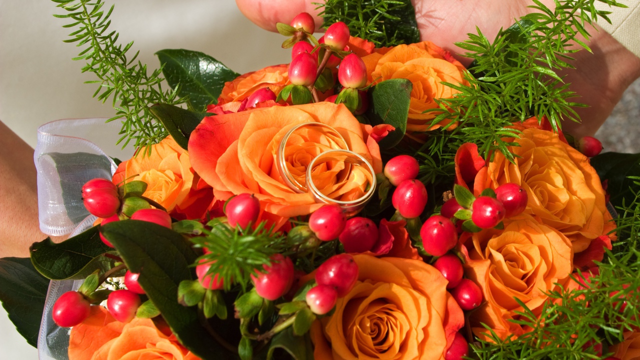Букет оранжевых роз с красными ягодами и обручальными кольцами