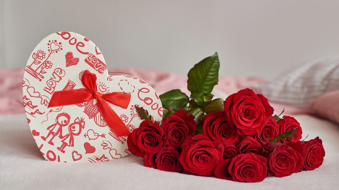 Букет красных роз с коробкой в форме сердца на кровати 