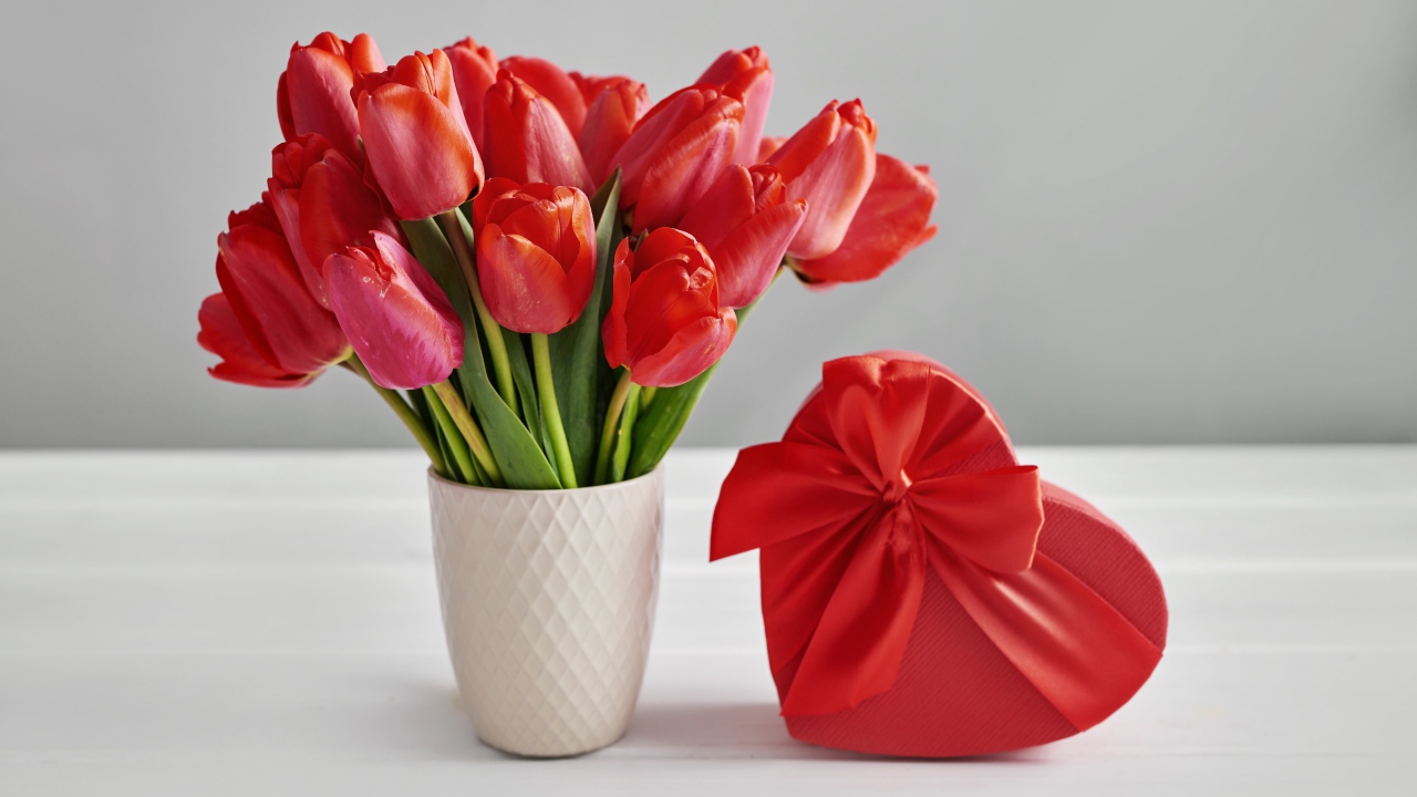 Букет красных тюльпанов на столе с коробкой в форме сердца