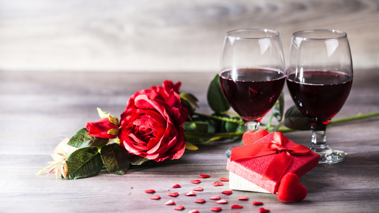 Розы, подарок и два бокала вина на столе