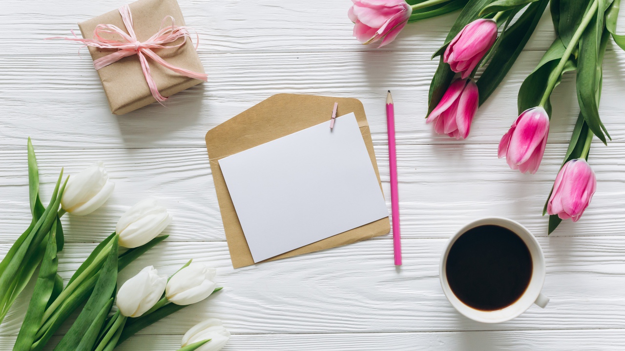 Два букета тюльпанов на столе с подарком, кофе и письмом