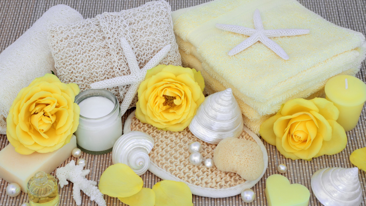 Желтые розы на столе с полотенцем, ракушками и мылом