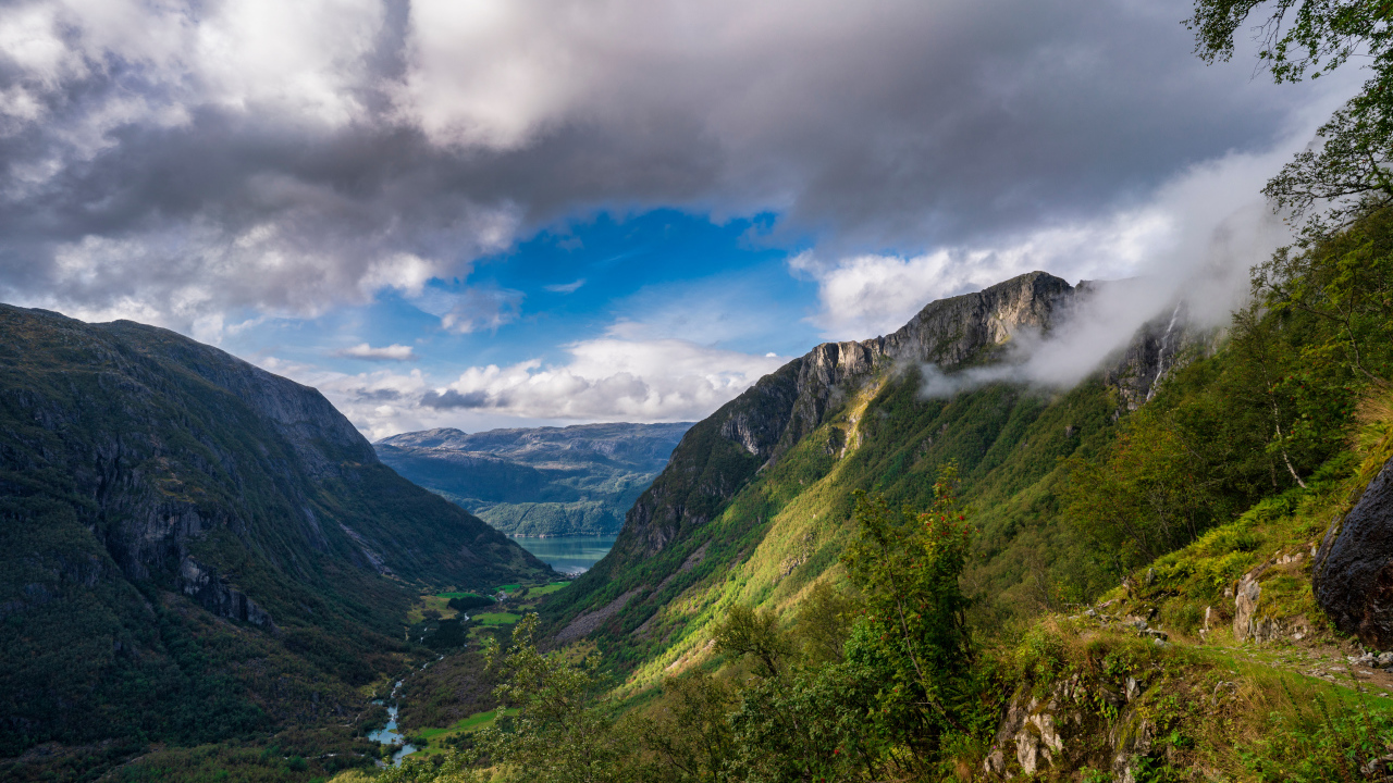 Покрытые зеленой растительностью горы под белыми облаками, Норвегия