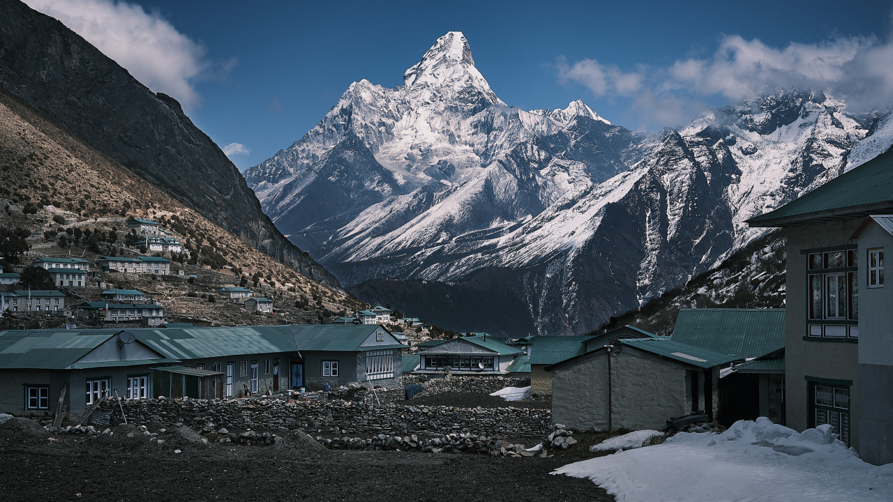 Поселок на фоне заснеженных гор под голубым небом 