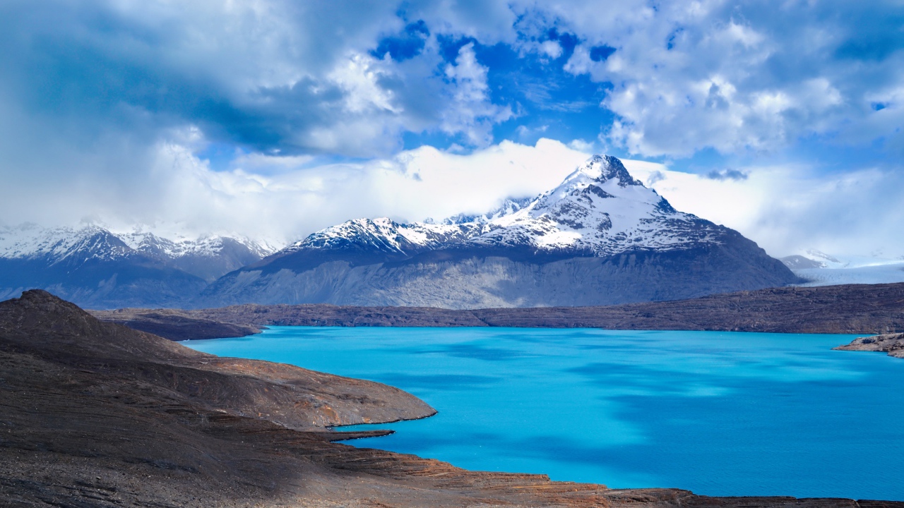 Вид на заснеженную вершину горы у голубого озера 