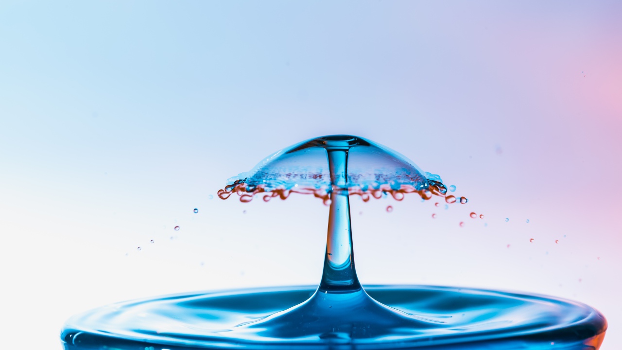 Зонтик из воды в стакане на сером фоне