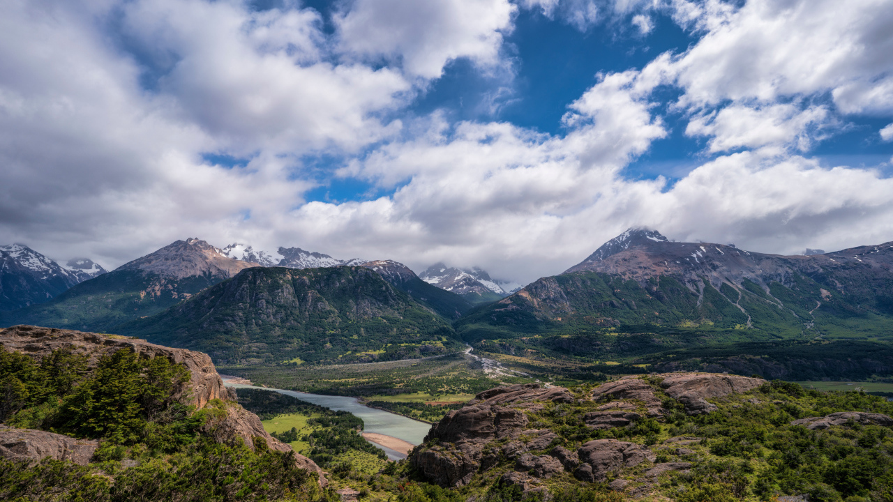 Белые облака в голубом небе над покрытыми зеленью горами