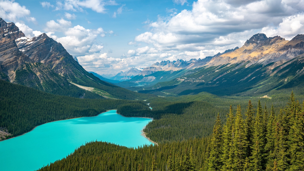 Вид на красивое голубое озеро и горную долину под солнечным небом с белыми облаками