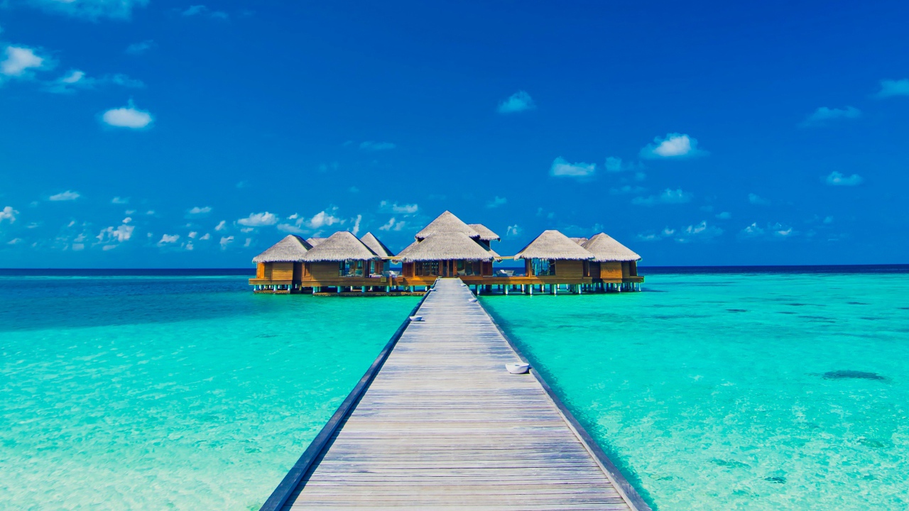 Деревянный мост к домам на сваях в голубом океане 