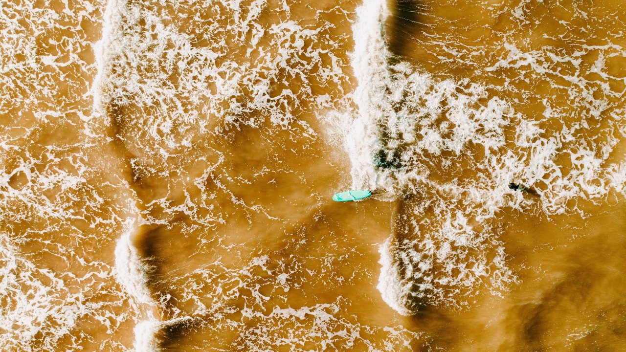 Белые волны на воде поднимают песок