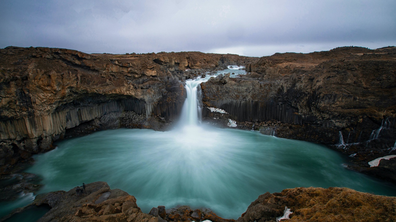 Красивый водопад стекает с каменной скалы в озеро 