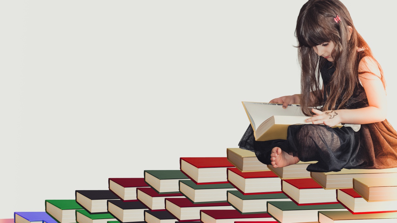 Маленькая девочка сидит на горе книг 