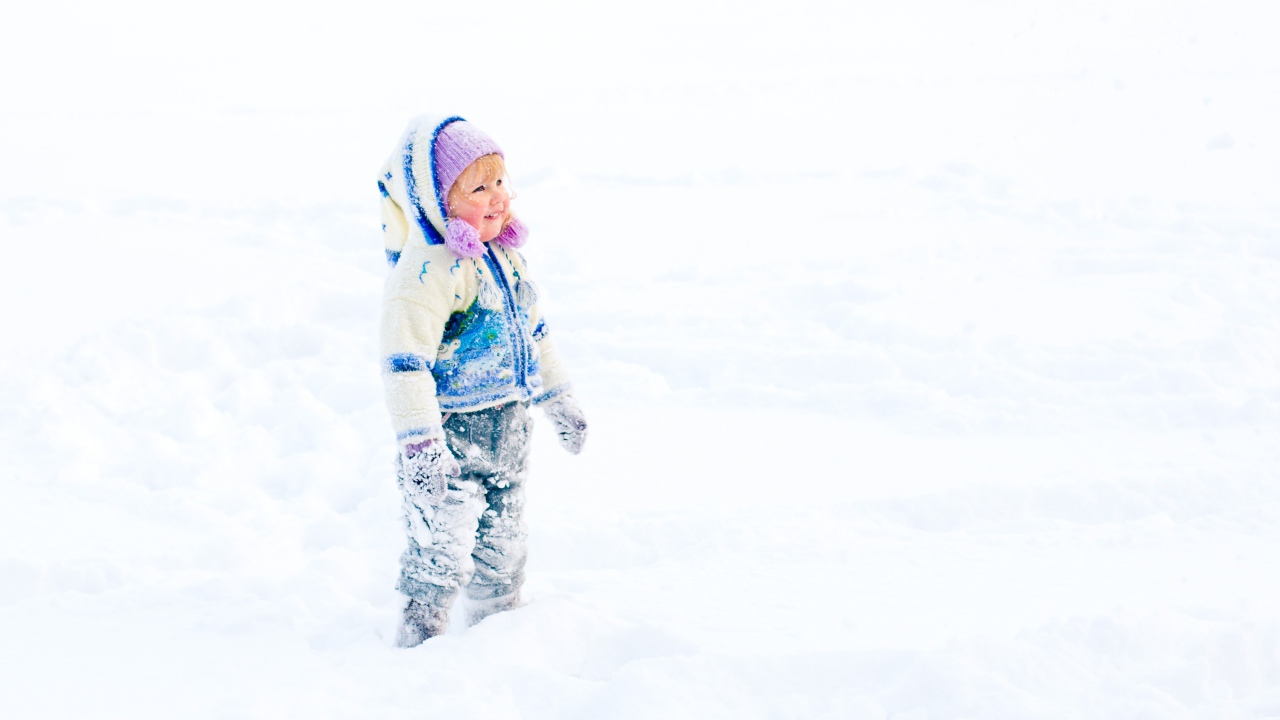 Маленькая веселая девочка гуляет по снегу