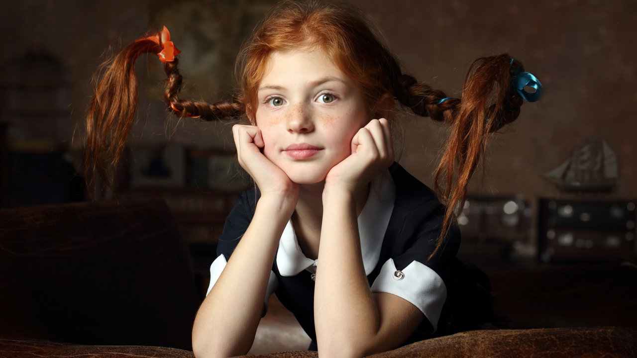 Маленькая смешная девочка с косами в школьной форме 