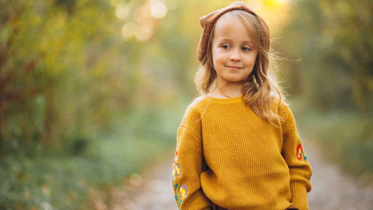 Маленькая девочка в свитере гуляет в лесу
