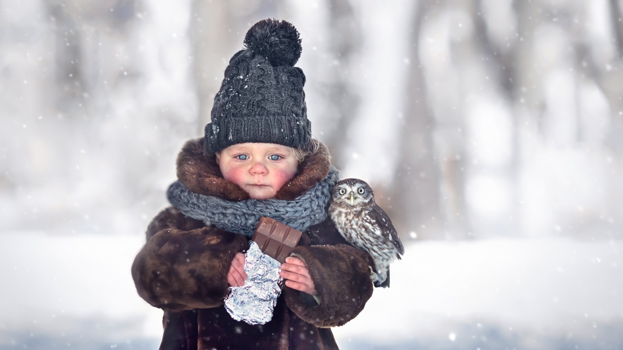 Маленькая девочка с шоколадкой в руках на улице зимой