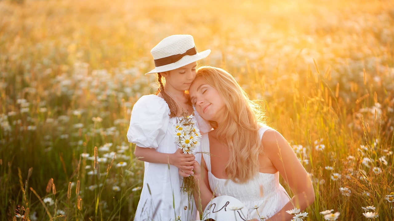 Мать с дочерью на поле с белыми ромашками в лучах солнца 