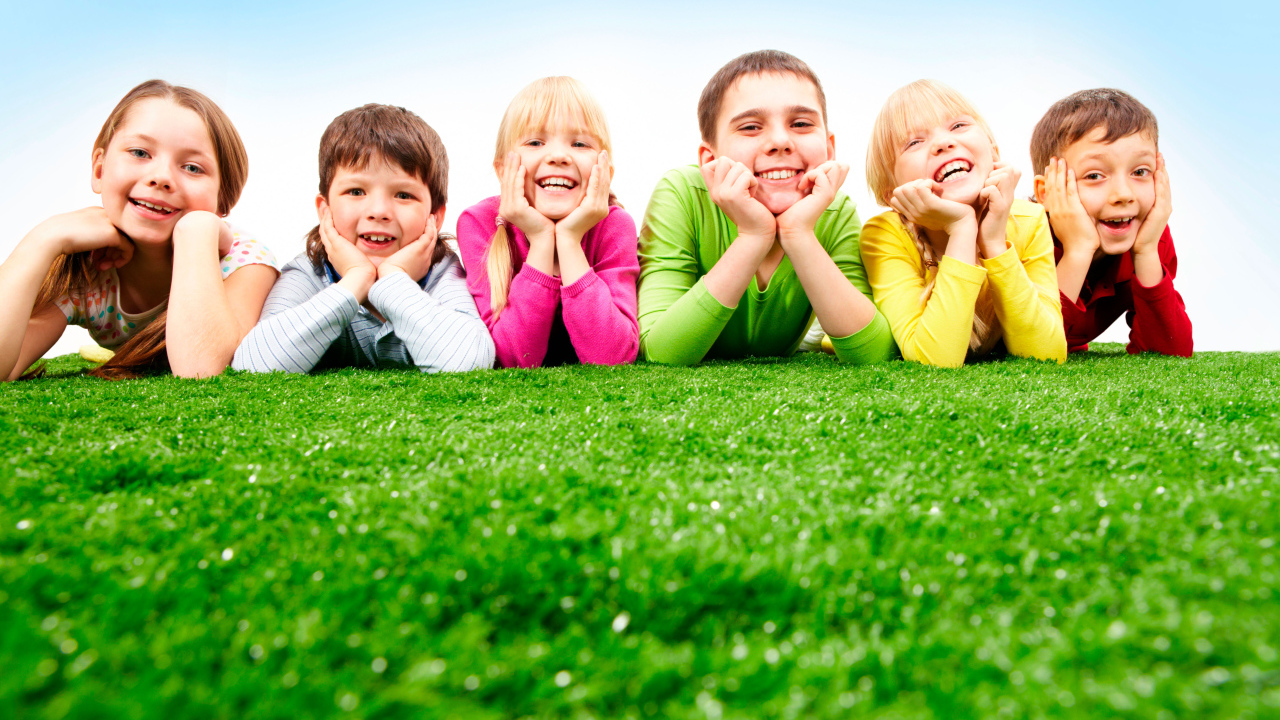 Улыбающиеся дети лежат на зеленой траве