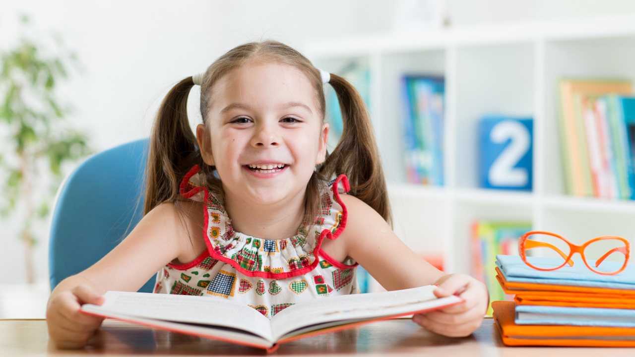 Улыбающаяся маленькая девочка с книгой 