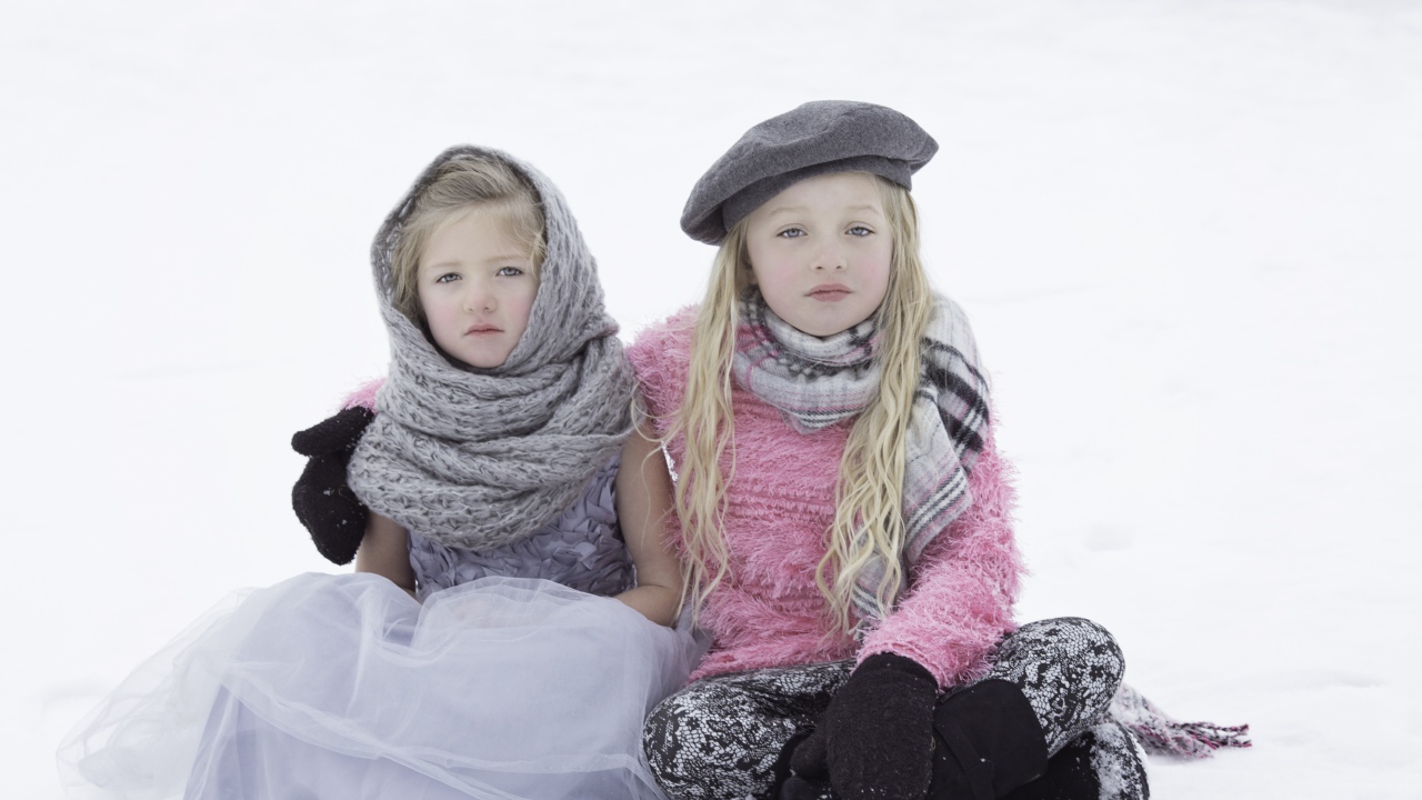 Две маленьких сестры сидят на снегу 