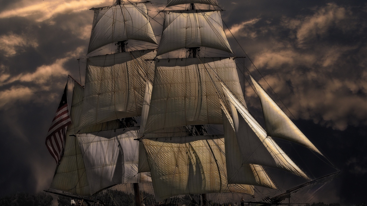 Больше судно с белыми парусами на фоне неба в сумерках 