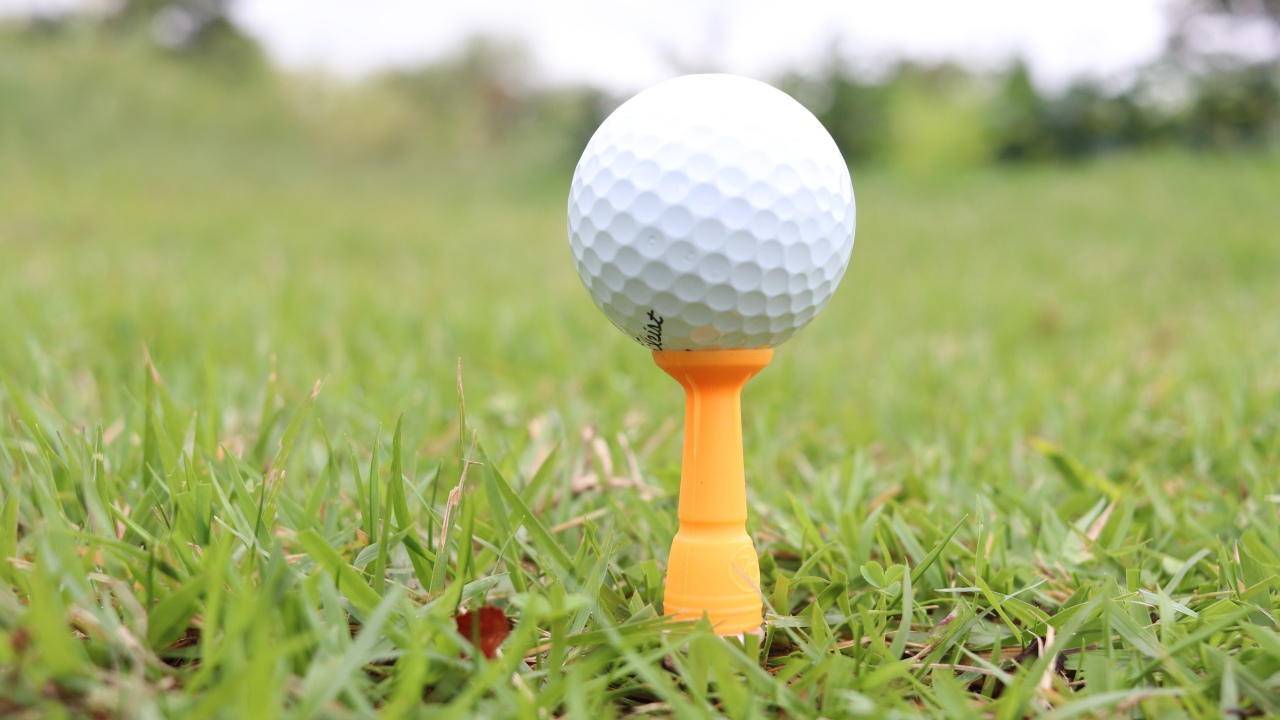 Мячик для гольфа на поле с зеленой травой 