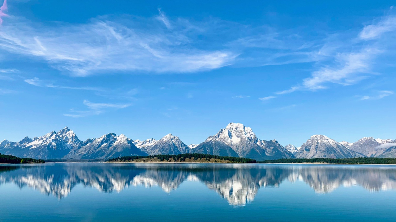 Вид на заснеженные горы под голубым небом у озера, Национальный парк Гранд Титон, Вайоминг. США
