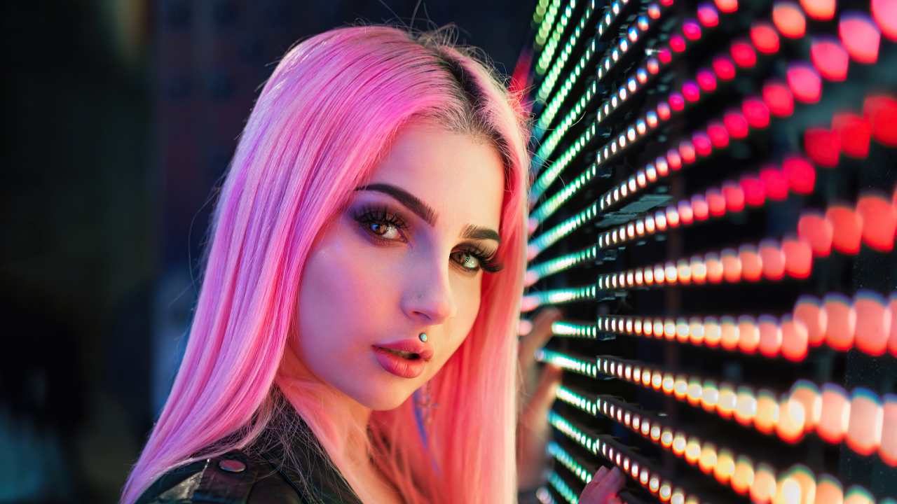 Beautiful girl with pink hair with light bulbs on the wall