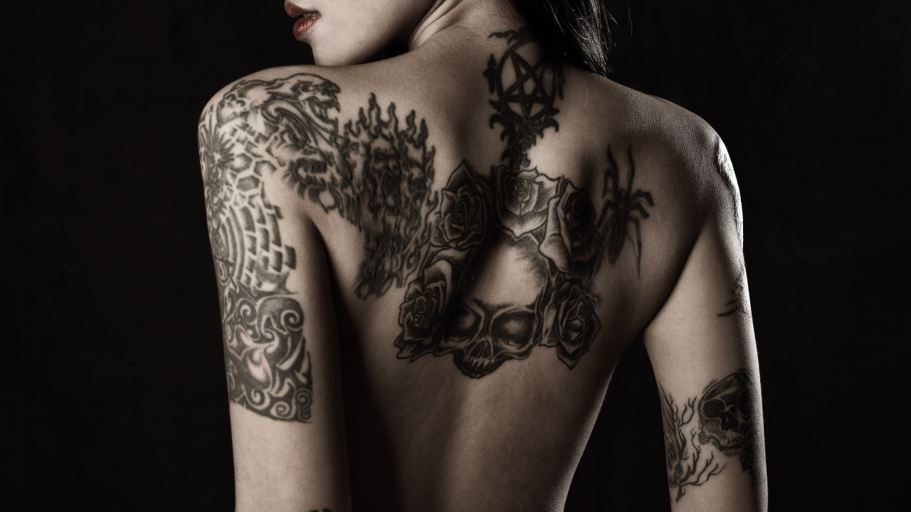 Девушка с татуировками на руках и спине