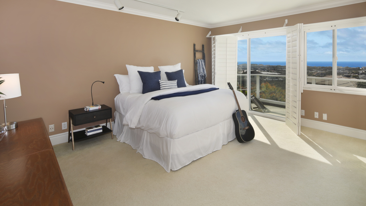 Большая высокая кровать в просторной спальне с гитарой 