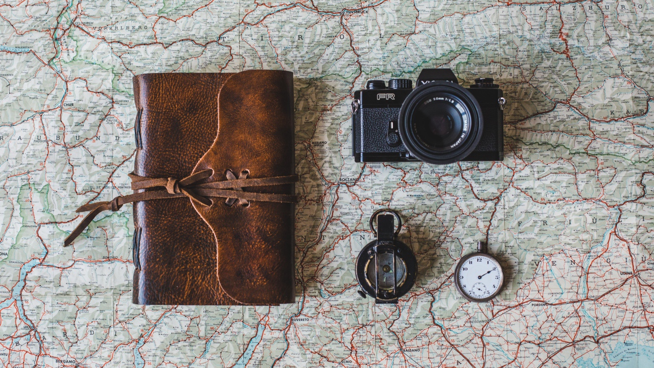 Старый фотоаппарат, компас, часы, блокнот и карта на столе