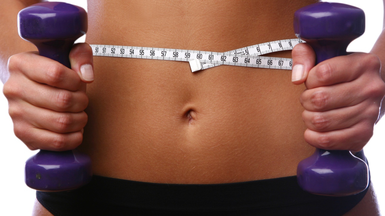 Стройная спортивная девушка с гантелями в руках 