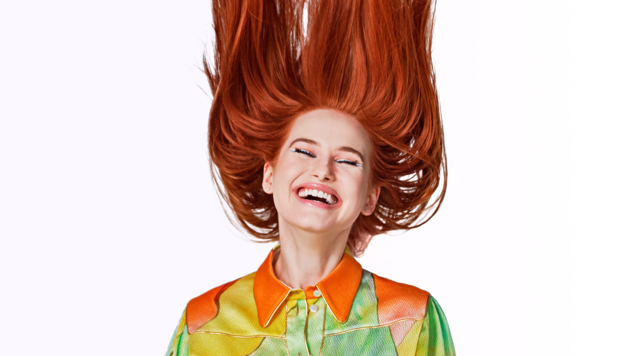 Улыбающаяся актриса Мэделин Петш с рыжими волосами на белом фоне