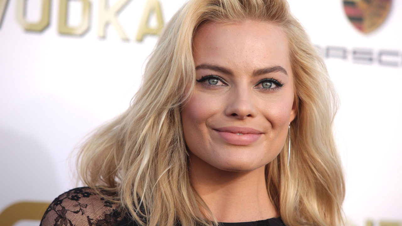 Улыбающаяся блондинка, актриса Марго Робби у стены