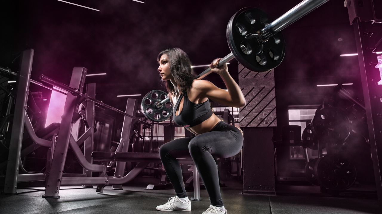 Девушка тяжелоатлет поднимает штангу в спортзале