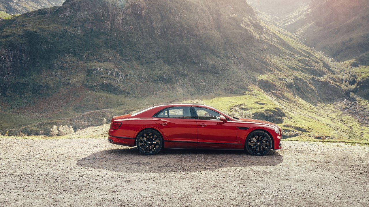 Красный автомобиль Bentley Flying Spur V8 2020 года у горы 