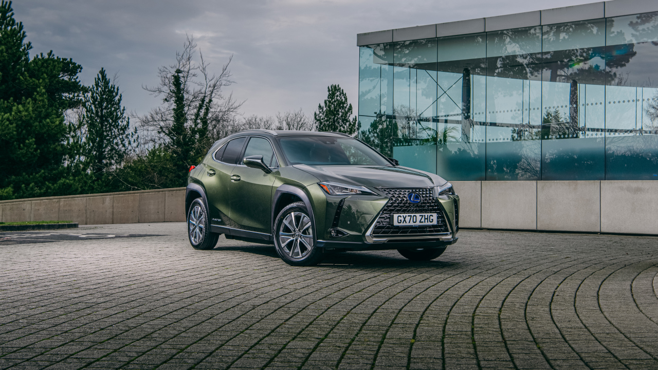 Зеленый автомобиль Lexus UX 300e 2021 года у стеклянной стены