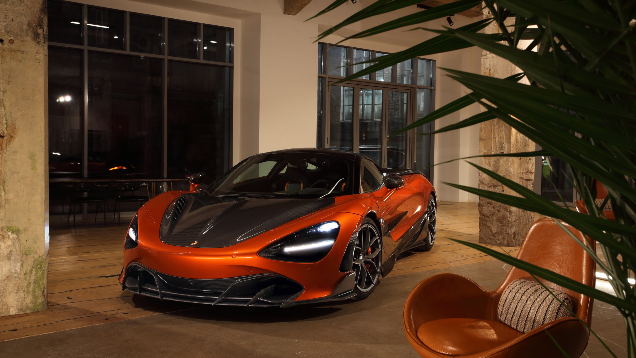 Оранжевый автомобиль  McLaren 720S у дома с креслом