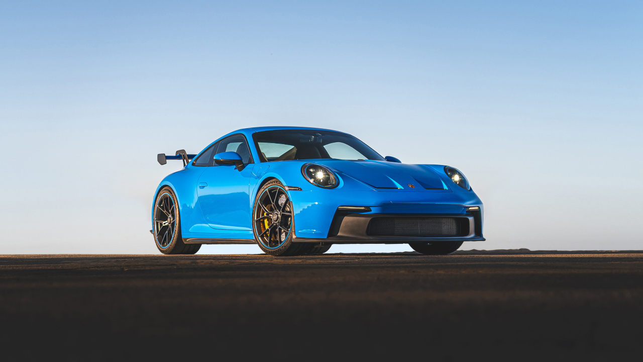 Синий автомобиль Porsche 911 GT3 2021 года на фоне неба