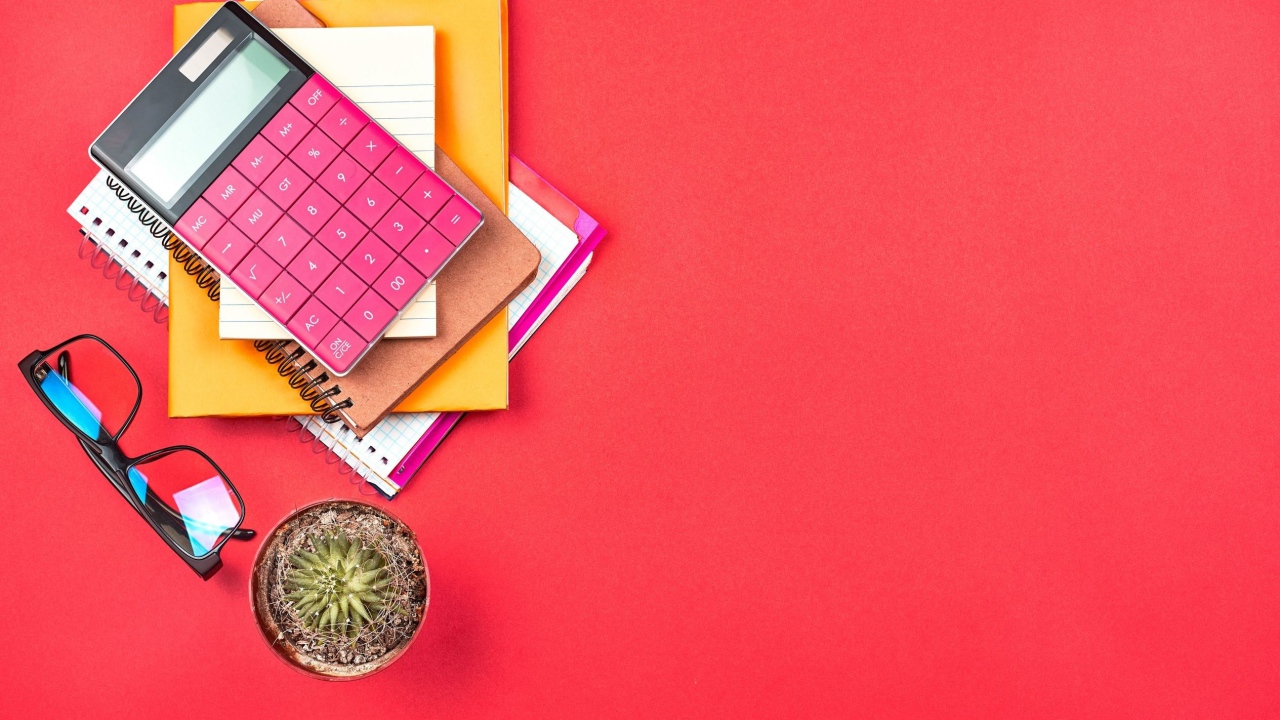 Калькулятор с очками и блокнотами на розовом фоне 