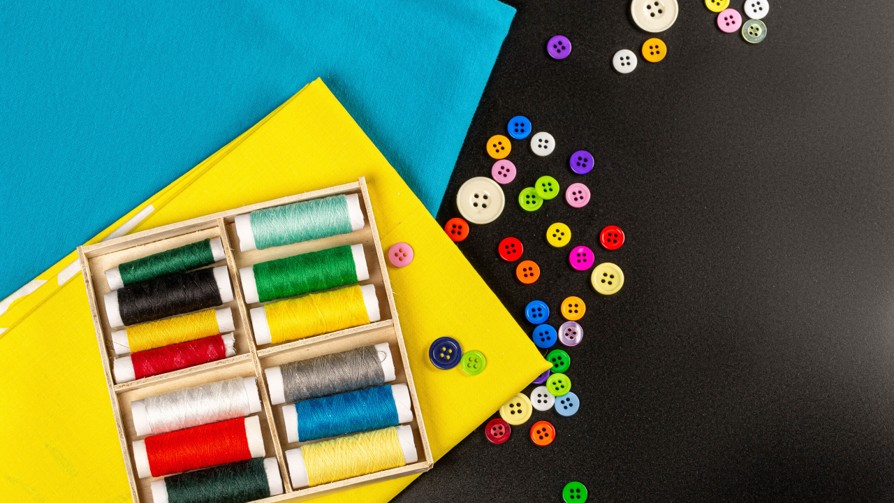 Разноцветные нитки, пуговицы и бумага на черном фоне 