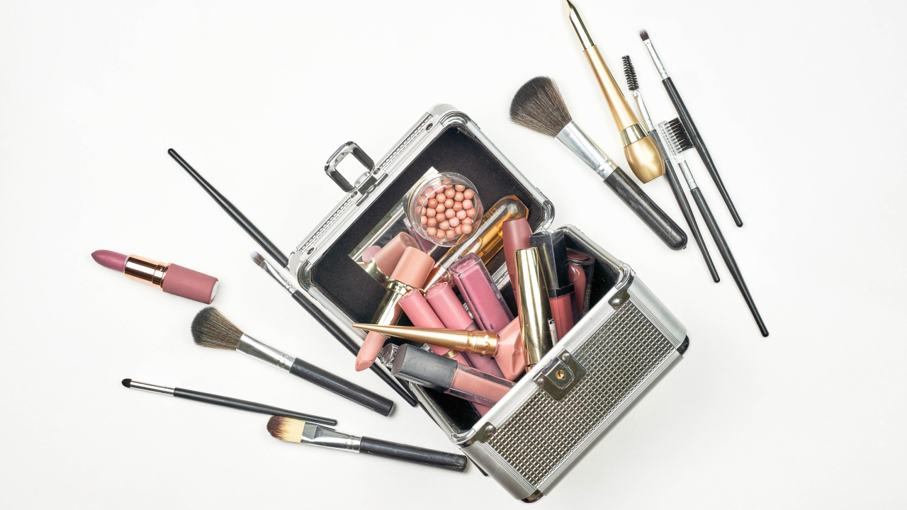 Набор косметики в чемодане на белом фоне