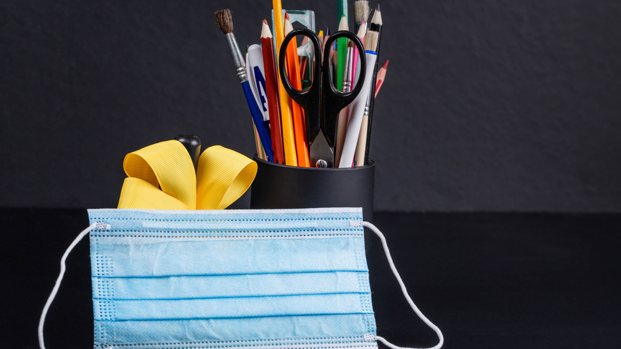 Канцелярские предметы на столе с медицинской маской
