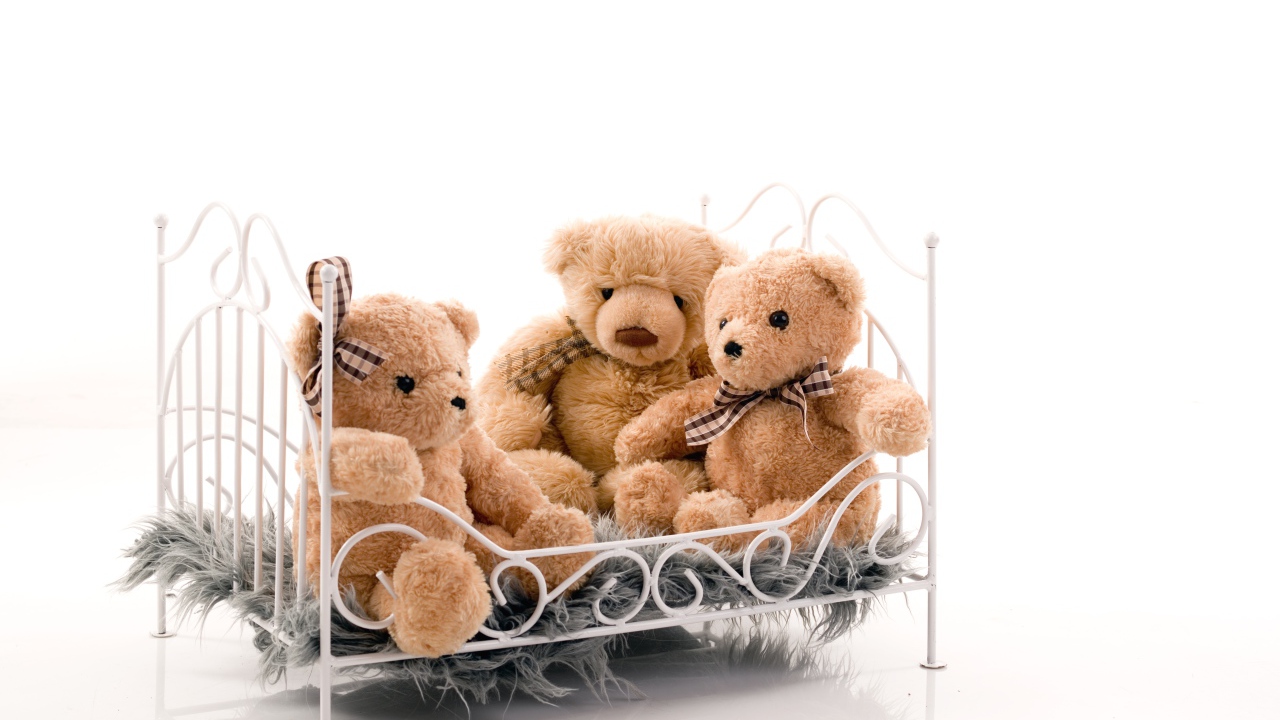 Три игрушечных медведя на кровати на белом фоне