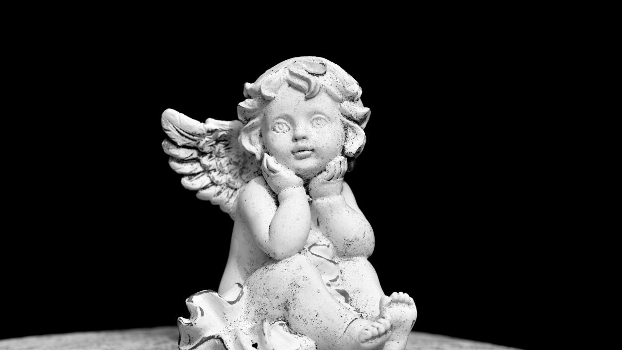 Белая статуэтка ангел на черном фоне