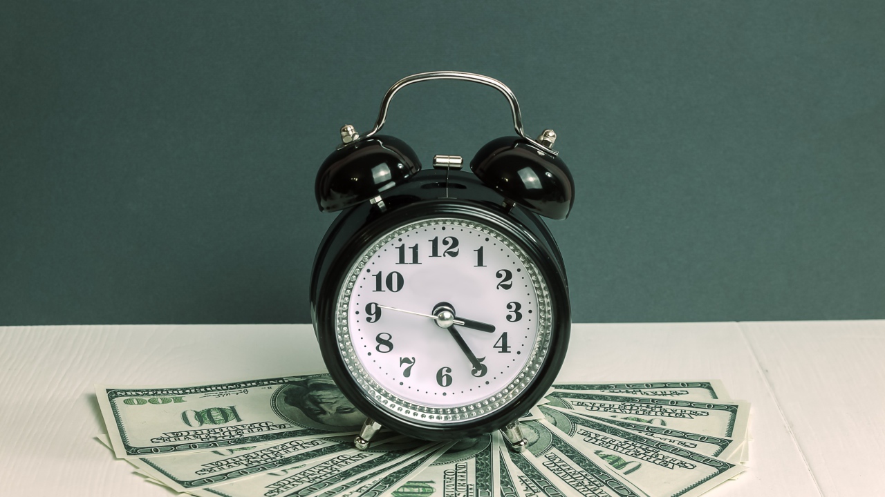 Черный будильник и доллары на столе