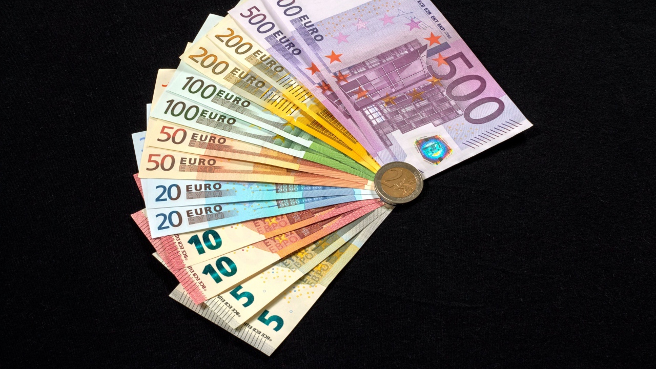 Пачка купюр евро с монетой на черном столе 